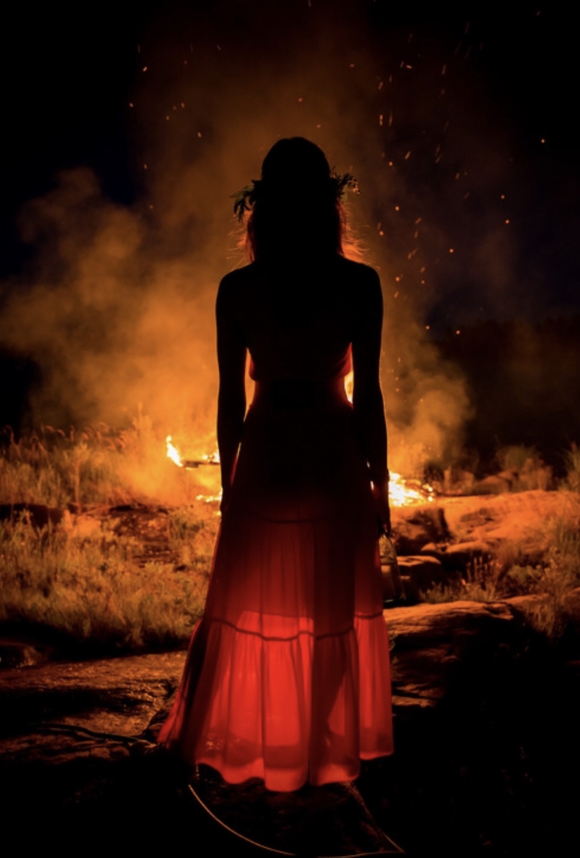 woman facing a fire shadow, dark feminine energy