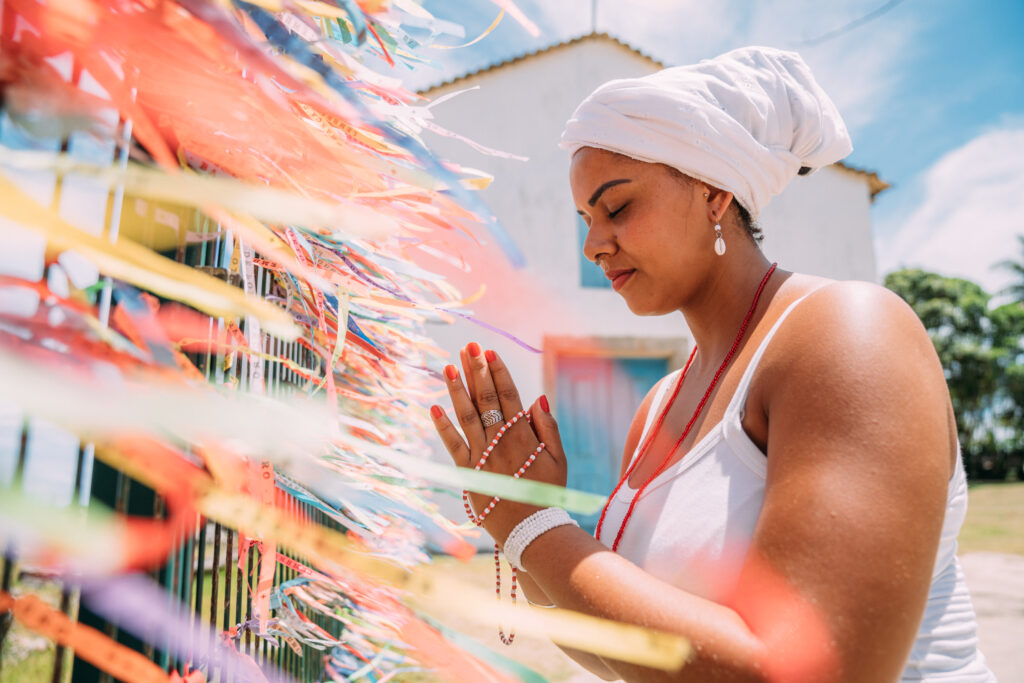 Brazilian woman dressed in the traditional Bahian costume of the Umbanda religion saying a prayer. focus on colored ribbons of religious promises in devotion to Senhor do Bonfim in Bahia, Brazil