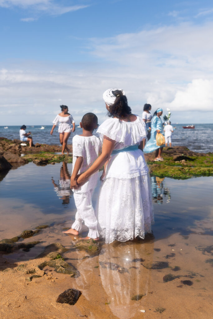 Salvador, Bahia, Brazil - February 02, 2023: Candomble people are in the water on the rocks of Rio Vermelho beach, offering gifts to Yemanja, in Salvador, Bahia. represents umbanda