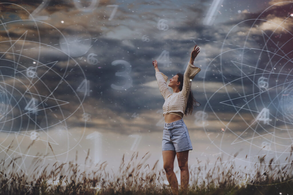 Joyful woman standing in a field with arms raised, surrounded by abstract numerology symbols, symbolizing law of attraction and the connection between numbers and the universe