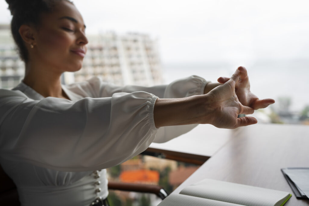 A woman taking a stretch break at her desk, integrating self-care into her conscious business routine