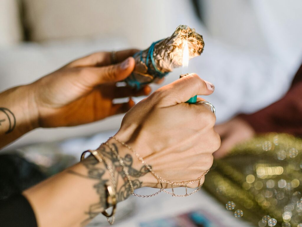 A person lighting a bundle of sage, symbolizing a cleansing ritual, related to the spiritual meaning of solar eclipse and personal transformation.