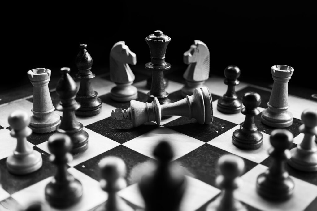 A captivating black and white photo of a chess game with fallen king piece, symbolizing defeat.