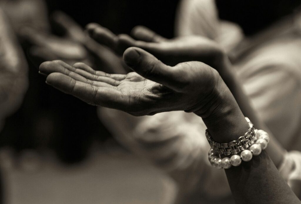 Close-up of expressive hands in prayer wearing a bracelet, conveying faith and devotion and suspectibility to New Age deception