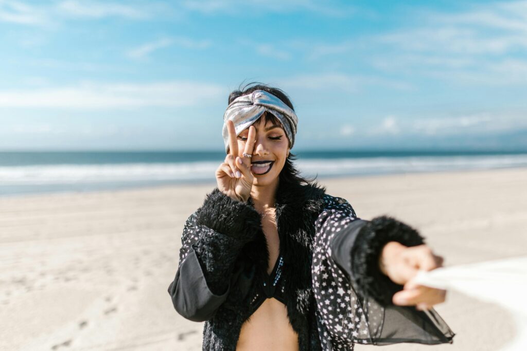 A woman having fun at the beach, showing a peace sign on a sunny day to illustrate new age deception