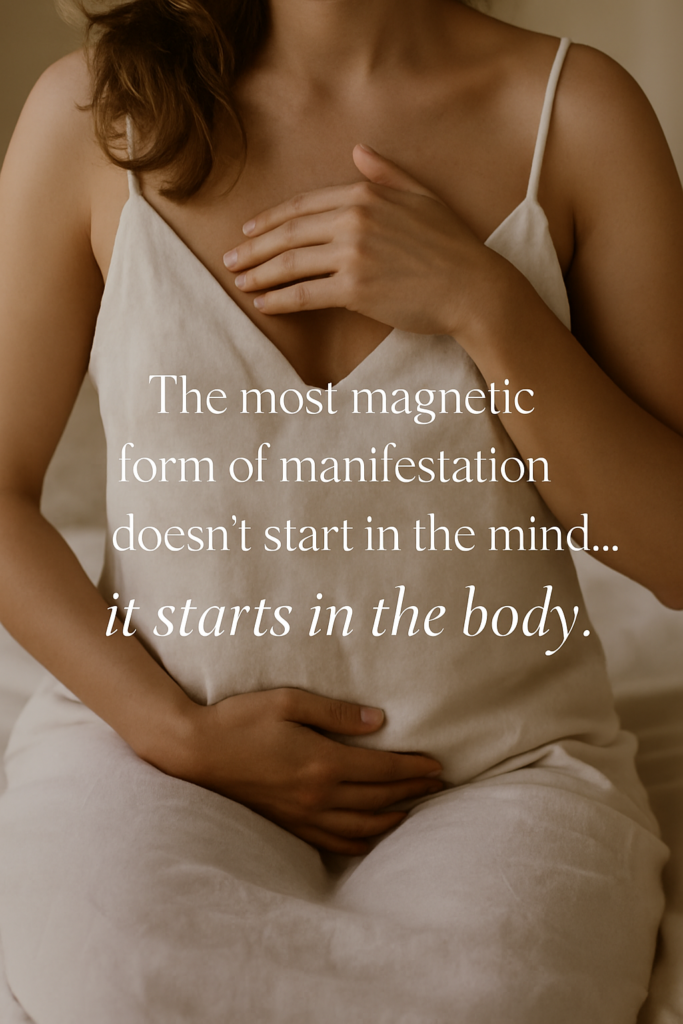 Woman in soft linen placing hands on heart and womb, illustrating the somatic manifestation process of anchoring desire through the body.
