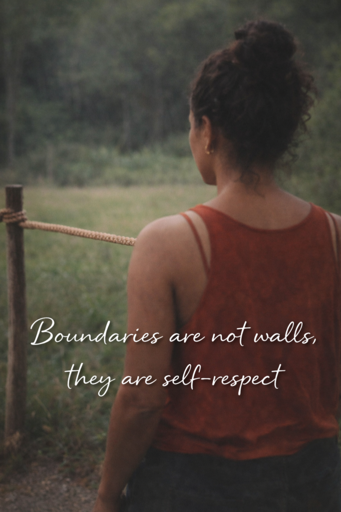 A woman stands outdoors facing a simple rope boundary stretched between two wooden posts, with soft green trees and grass blurred in the background. She wears an orange sleeveless top and has her hair tied up in a bun, looking out quietly into the open space. Text across the image reads, “Boundaries are not walls, they are self-respect.”