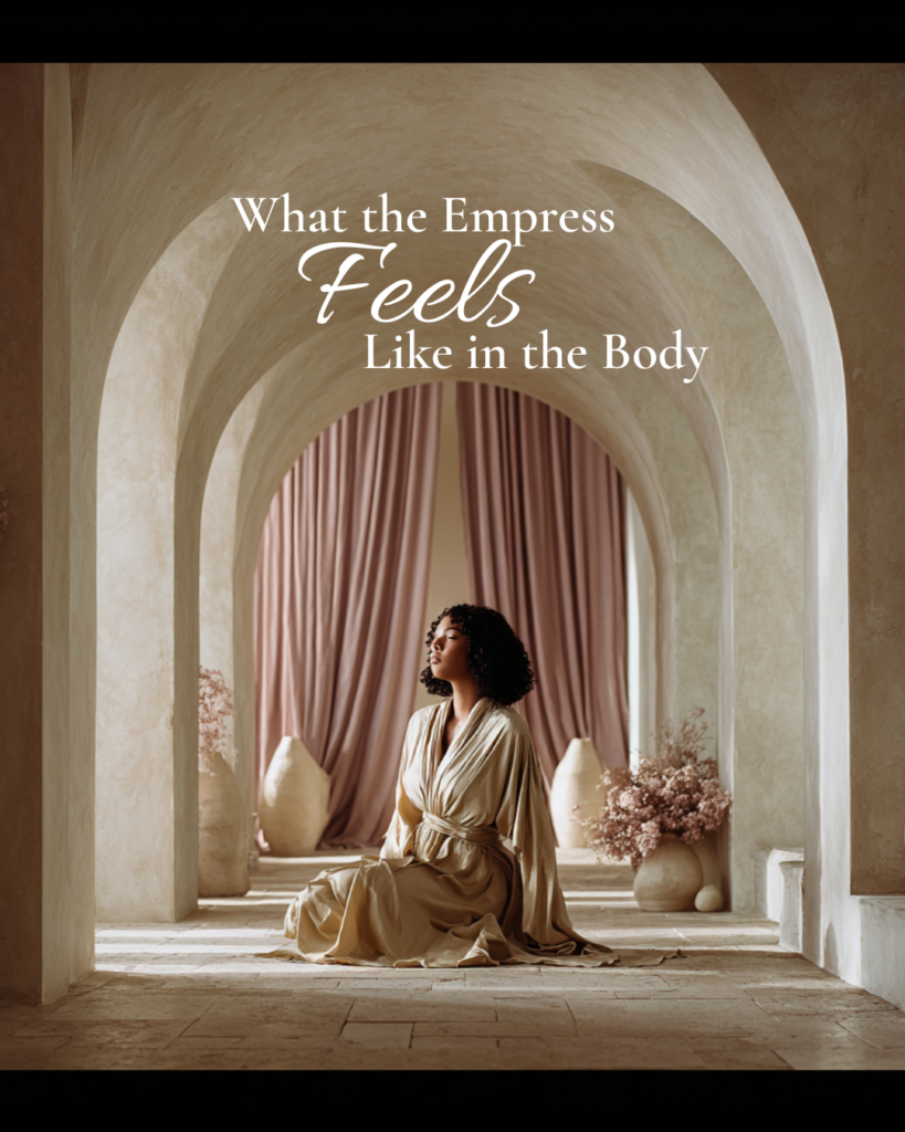 A woman seated calmly beneath soft stone arches, eyes closed and posture relaxed, embodying the Empress archetype through grounded ease, open presence, and embodied feminine power.